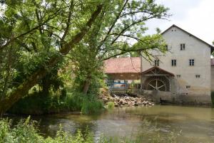 Wassermühle mit Bäumen am gegenüberliegendem Ufer